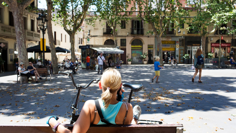 Vista general de la plaça de la Concòrdia amb una noia asseguda en un banc. Autoria: Paola de Grenet